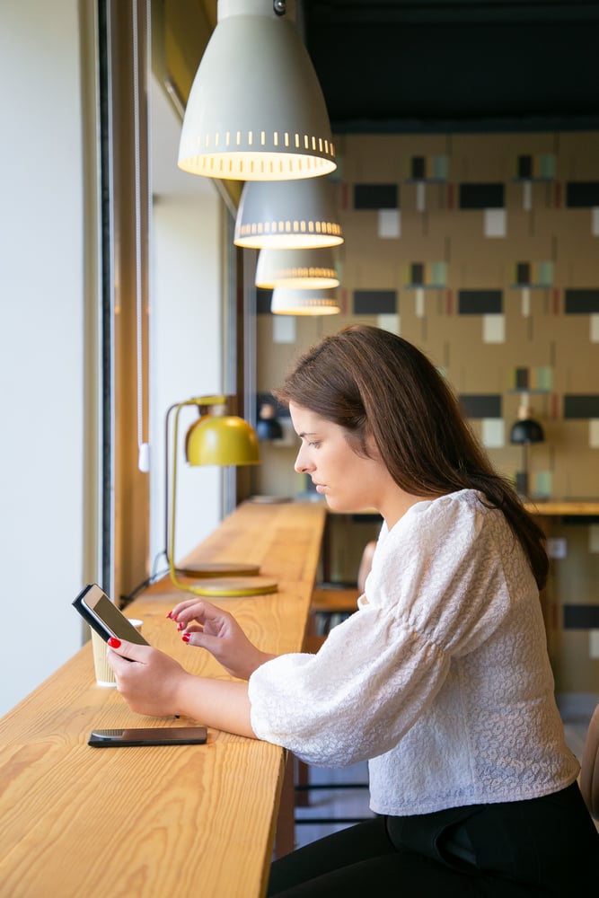focused-female-manager-using-tablet-while-sitting-desk-co-working-space-coffee-shop